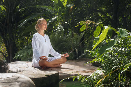 Portrait of young woman practicing yoga in tropic environmentの写真素材