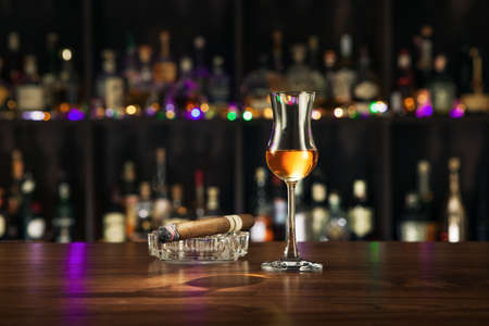 NO LOGOS OR TRADEMARKS!  SELF MADE LABELS! close up view of cigar  and a glass of rum on color back.の写真素材