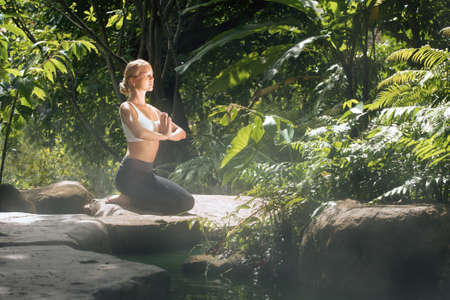 Portrait of young woman practicing yoga in tropic environmentの写真素材