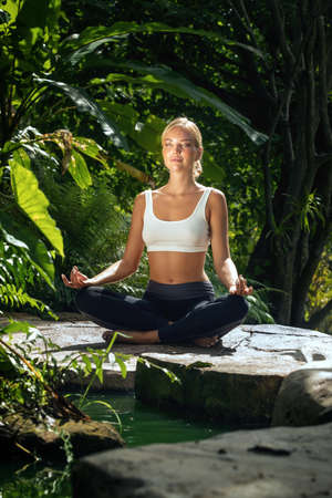 Portrait of young woman practicing yoga in tropic environmentの写真素材