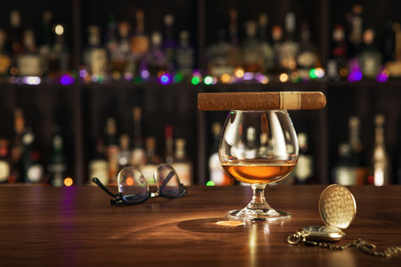 Closed up view of glass of cognac with cigar on color backの写真素材