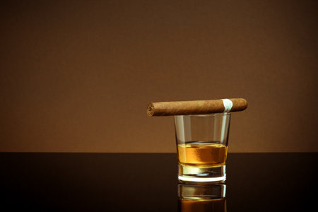 Closed up view of glass of whiskey with cigar on top on white backの写真素材