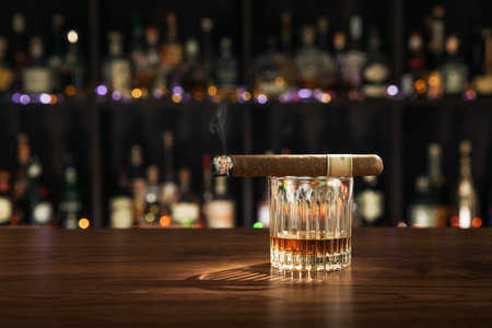 Closed up view of glass of whiskey with cigar on top on white backの写真素材