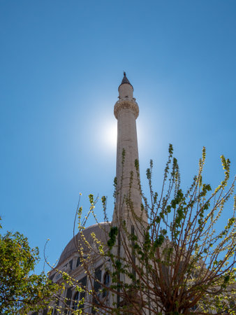 Minaret in Turkey standing out against the blue sky, with sunrays behind it.
