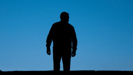Freedom. Silhouette of sad, despair, lonely man stand on the street, front of isolated blue open sky.の写真素材
