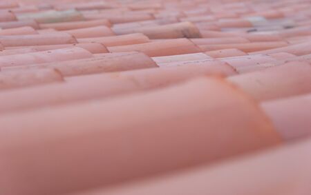 Red corrugated tile element of roof tile pattern on house. Close up, selective focus.