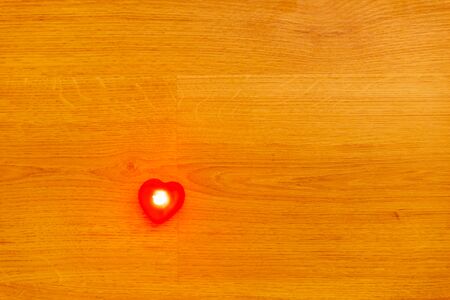 Red heart shape light on the wooden background for Valentine's Day.
