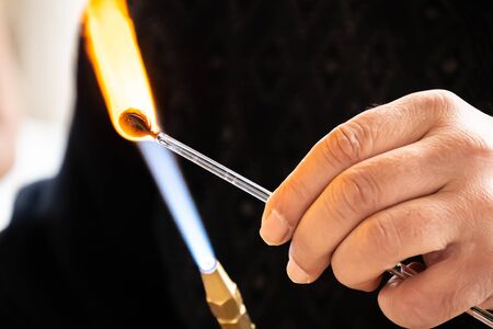 Hands of the handicrafts man making a glass subject of crafts. Glass maker working melted glass with...