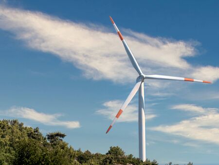 Wind turbine with beautiful clouds on the sky background. Renewable alternative energy.