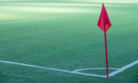 Soccer field with a corner red flag and flag pole.