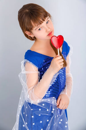 Beautiful child girl  holding a lollipop in the shape of a red heart valentines dayの写真素材
