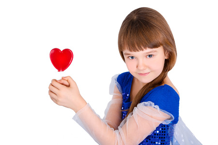 Beautiful child girl  holding a lollipop in the shape of a red heart valentines dayの写真素材