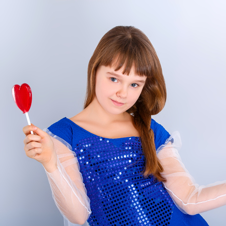 Beautiful child girl  holding a lollipop in the shape of a red heart valentines dayの写真素材
