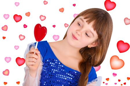 Beautiful child girl  holding a lollipop in the shape of a red heart valentines dayの写真素材