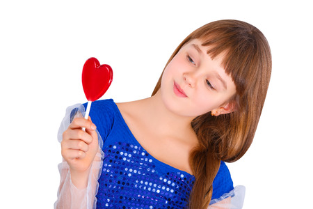 Beautiful child girl  holding a lollipop in the shape of a red heart valentines dayの写真素材