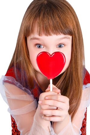 Beautiful child girl  holding a lollipop in the shape of a red heart valentines dayの写真素材