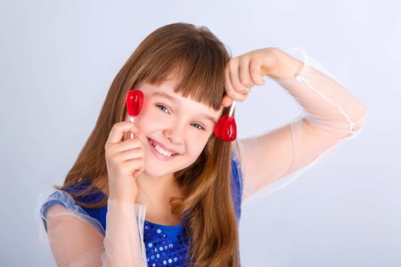 Beautiful child girl  holding a lollipop in the shape of a red heart valentines dayの写真素材