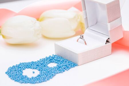 tulip and gold engagement ring on a white background