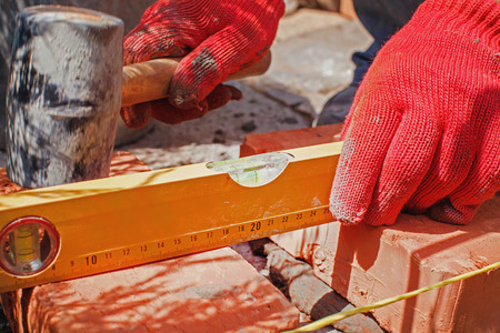 Bricklayer with brick at a construction siteの写真素材