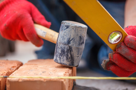 Bricklayer with brick at a construction siteの写真素材
