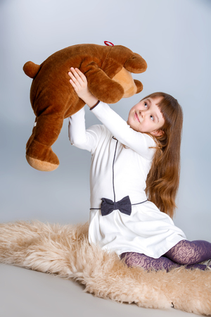 A portrait of a young pretty girl smiling and hugging her teddy bearの写真素材