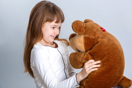 A portrait of a young pretty girl smiling and hugging her teddy bearの写真素材