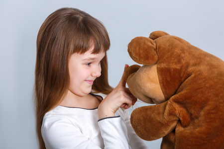 A portrait of a young pretty girl smiling and hugging her teddy bearの写真素材