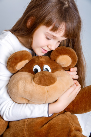 A portrait of a young pretty girl smiling and hugging her teddy bearの写真素材