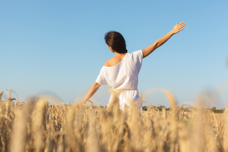 girl enjoy with sunshine in wheat field. Young  woman in white dress in wheat field