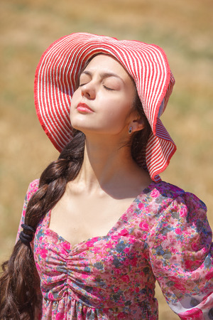 Happy girl in hat on wheat field. Big hat and blowing long hairの写真素材