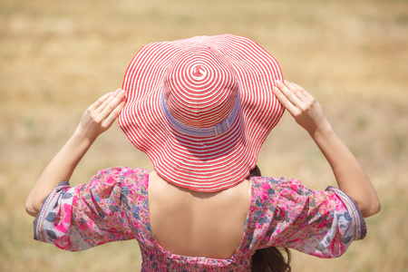 Happy girl in hat on wheat field. Big hat and blowing long hairの写真素材