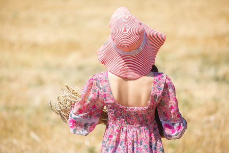 Happy girl in hat on wheat field. Big hat and blowing long hairの写真素材