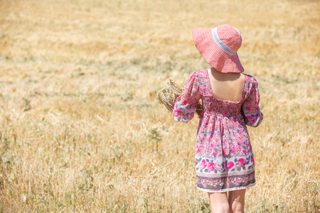 Happy girl in hat on wheat field. Big hat and blowing long hairの写真素材