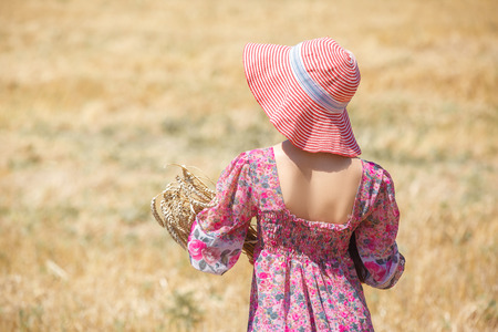 Happy girl in hat on wheat field. Big hat and blowing long hairの写真素材