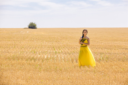 Young  woman in yellow dress in wheat fieldの写真素材