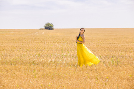Young  woman in yellow dress in wheat fieldの写真素材