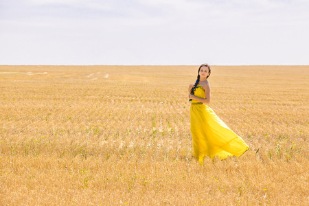 Young  woman in yellow dress in wheat fieldの写真素材