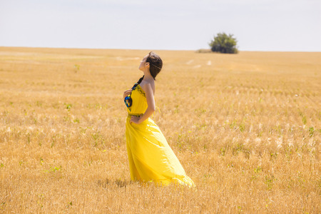 Young  woman in yellow dress in wheat fieldの写真素材