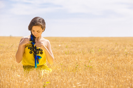 Young  woman in yellow dress in wheat fieldの写真素材
