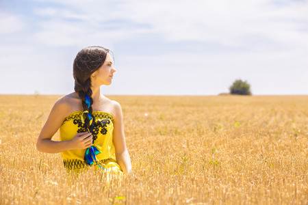 Young  woman in yellow dress in wheat fieldの写真素材