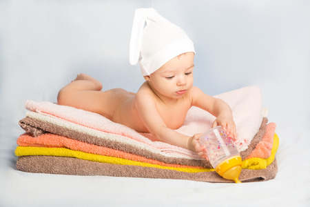 baby on colorful towels stack. baby  holding milk from bottleの写真素材