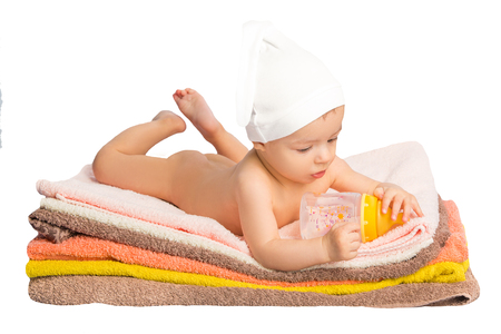 baby on colorful towels stack. baby  holding milk from bottleの写真素材
