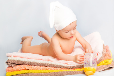 baby on colorful towels stack. baby  holding milk from bottleの写真素材