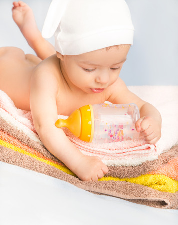 baby on colorful towels stack. baby  holding milk from bottleの写真素材