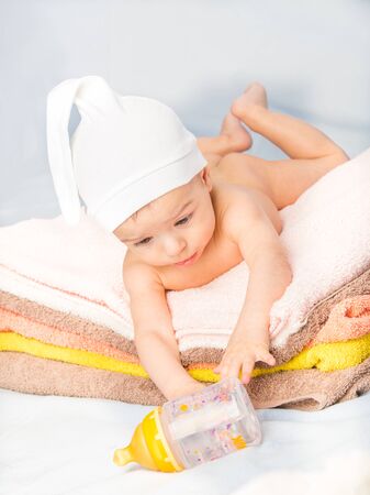 baby on colorful towels stack. baby  holding milk from bottleの写真素材