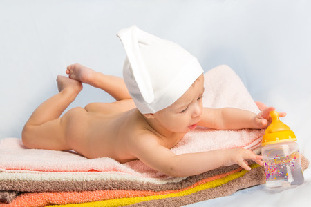 baby on colorful towels stack. baby  holding milk from bottleの写真素材