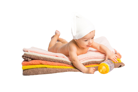 baby on colorful towels stack. baby  holding milk from bottleの写真素材