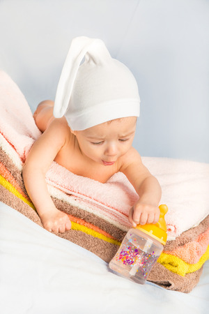 baby on colorful towels stack. baby  holding milk from bottleの写真素材