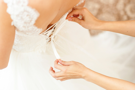 Bridesmaid is helping the bride to dressの写真素材