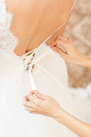 Bridesmaid is helping the bride to dressの写真素材